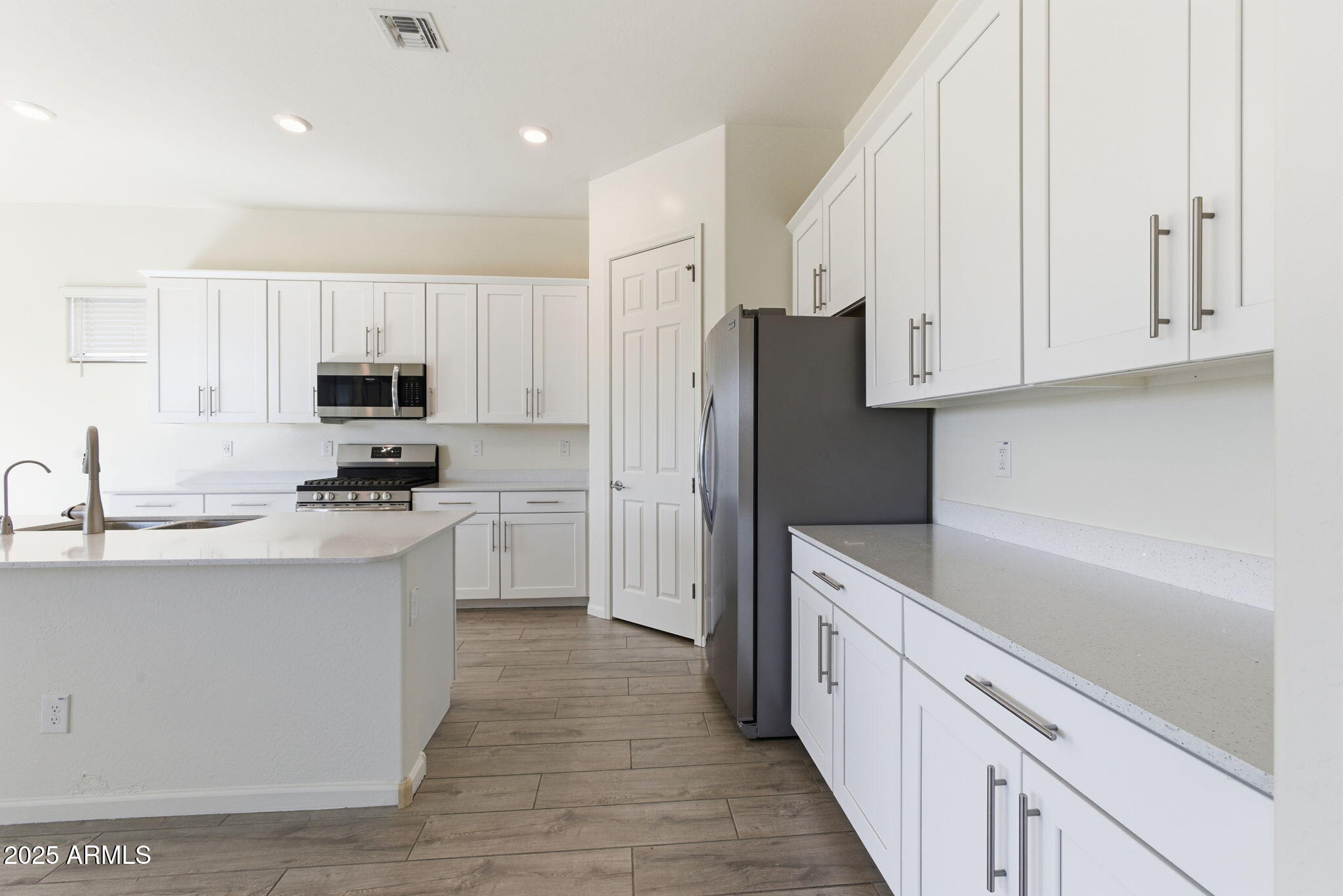 18545 West Chuckwalla Canyon Road Goodyear, AZ 85338 - Photo 6 of 26 a kitchen with stainless steel appliances granite countertop a refrigerator sink and white cabinets