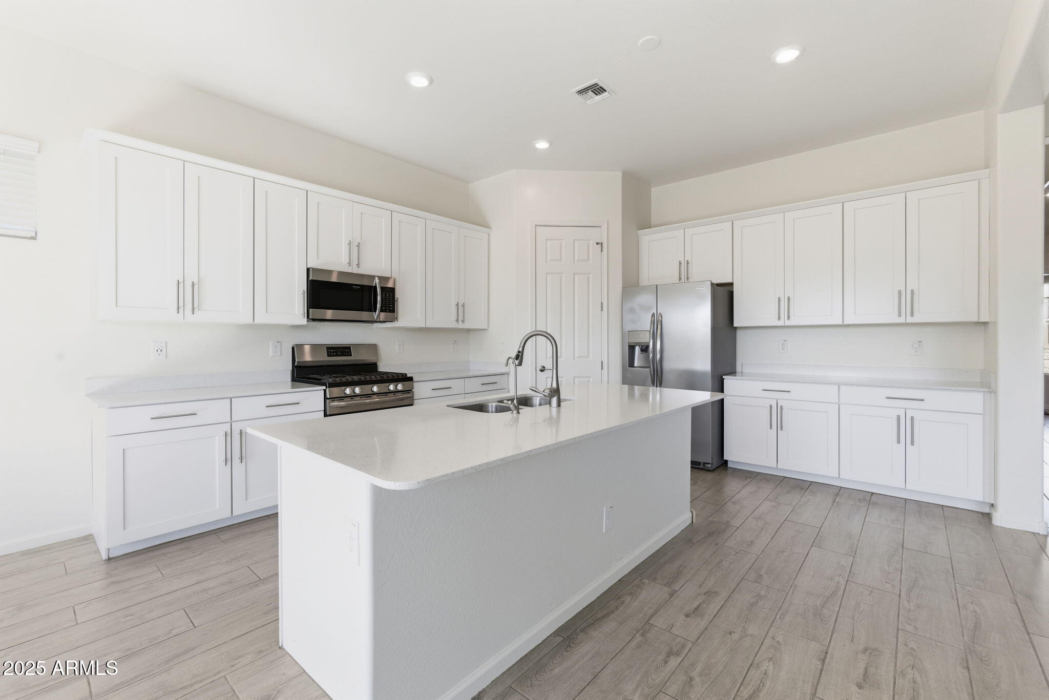 18545 West Chuckwalla Canyon Road Goodyear, AZ 85338 - Photo 7 of 26 a kitchen with white cabinets stainless steel appliances and sink