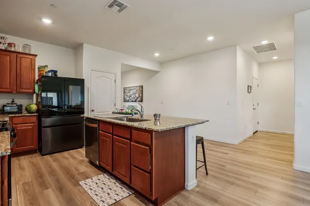 a kitchen with stainless steel appliances granite countertop a stove a sink dishwasher and a refrigerator with wooden floor