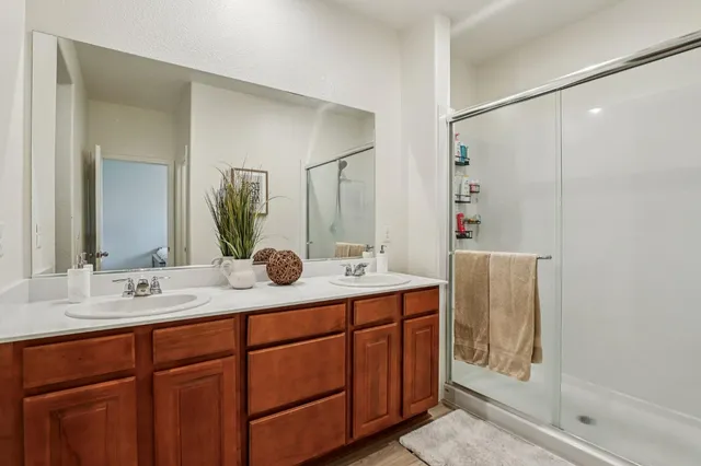 a bathroom with a double vanity sink mirror and shower