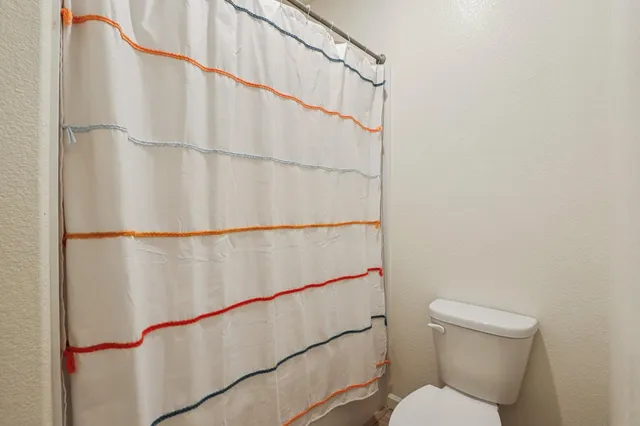 a bathroom with a toilet and a shower curtain