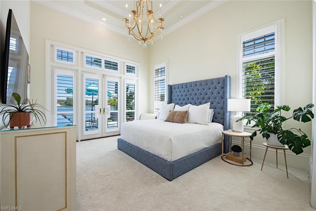 13741 Pondview Circle Naples, FL 34119 - Photo 36 of 50 a spacious bedroom with a bed and a chandelier
