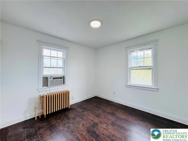 an empty room with a window and wooden floor