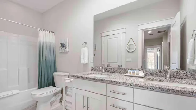 a bathroom with a granite countertop sink toilet mirror and a shower