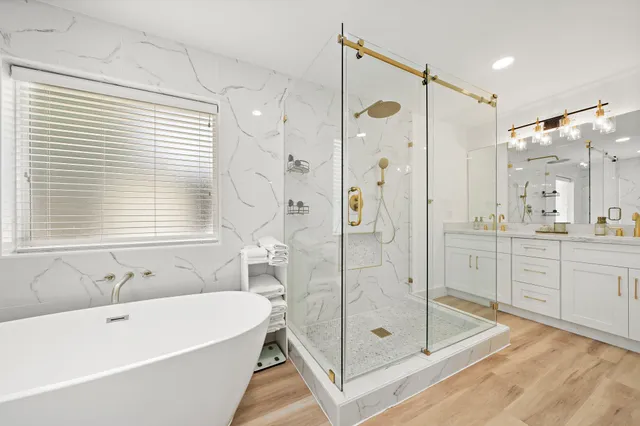 a bathroom with a tub shower sink mirror and a shower