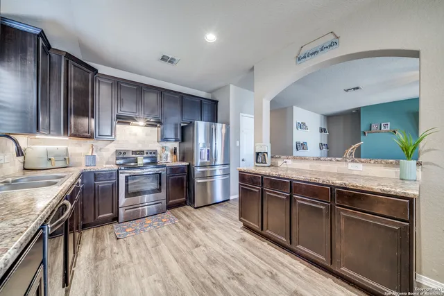 a large kitchen with stainless steel appliances granite countertop a stove refrigerator and cabinets