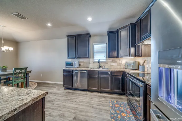 a large kitchen with stainless steel appliances granite countertop a stove refrigerator a sink dishwasher and wooden cabinets with wooden floor