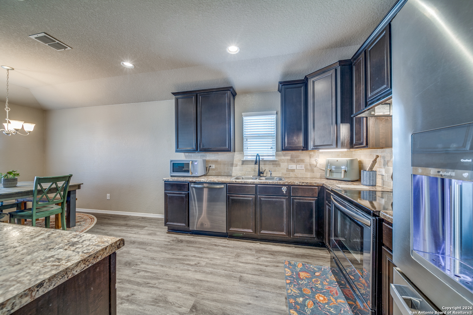 7211 Marina Del Rey Converse, TX 78109 - Photo 9 of 25 a large kitchen with stainless steel appliances granite countertop a stove refrigerator a sink dishwasher and wooden cabinets with wooden floor