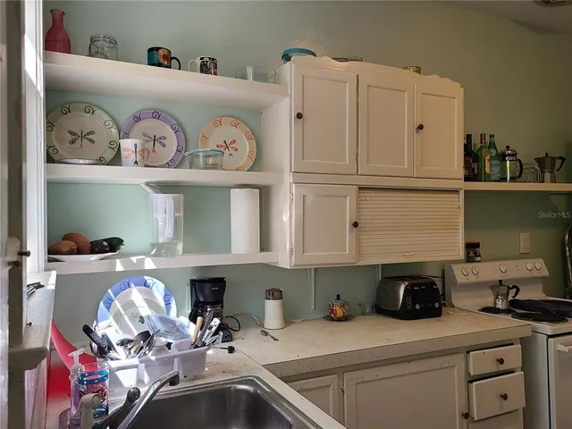 a kitchen with white cabinets and sink