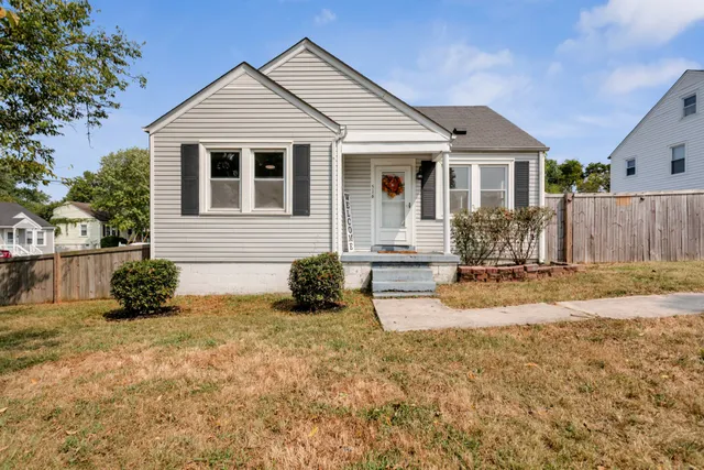 a view of a yard in front of a house with wooden fence