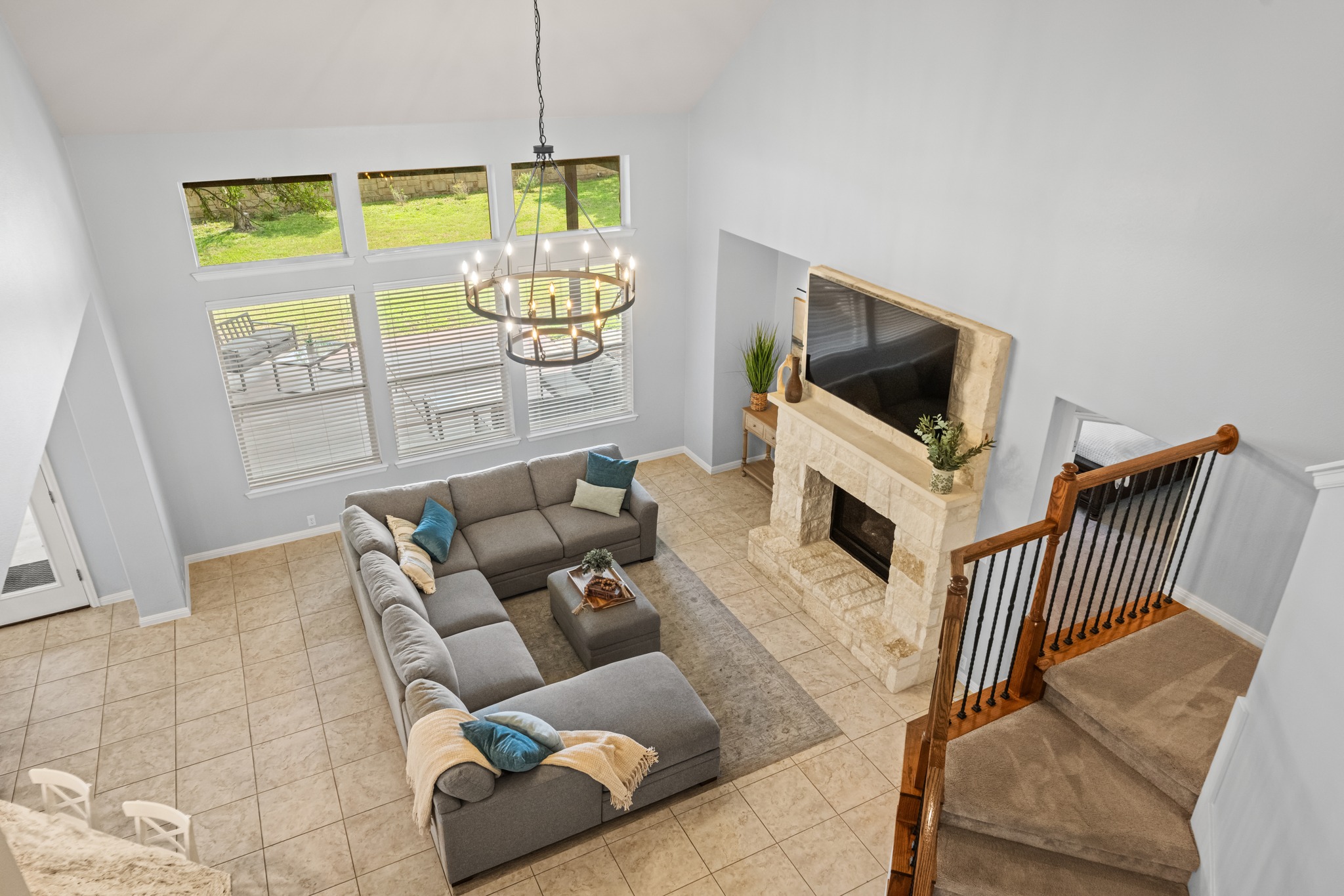 1023 Grassy Field Road Austin, TX 78737 - Photo 22 of 40 Great room featuring a vaulted ceiling with an iron chandelier, a stone fireplace, large windows with outdoor patio access, and tile flooring