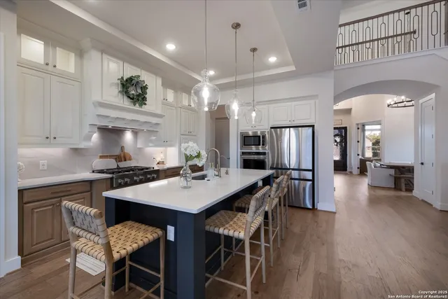 a kitchen with stainless steel appliances kitchen island granite countertop a table chairs stove and refrigerator