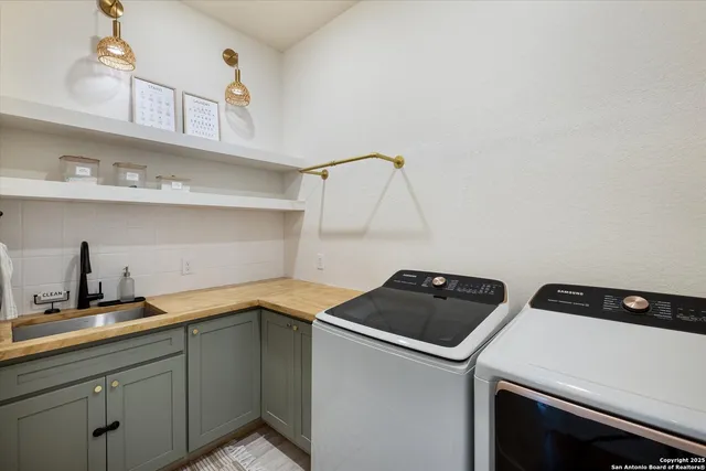 a utility room with sink dryer and cabinets