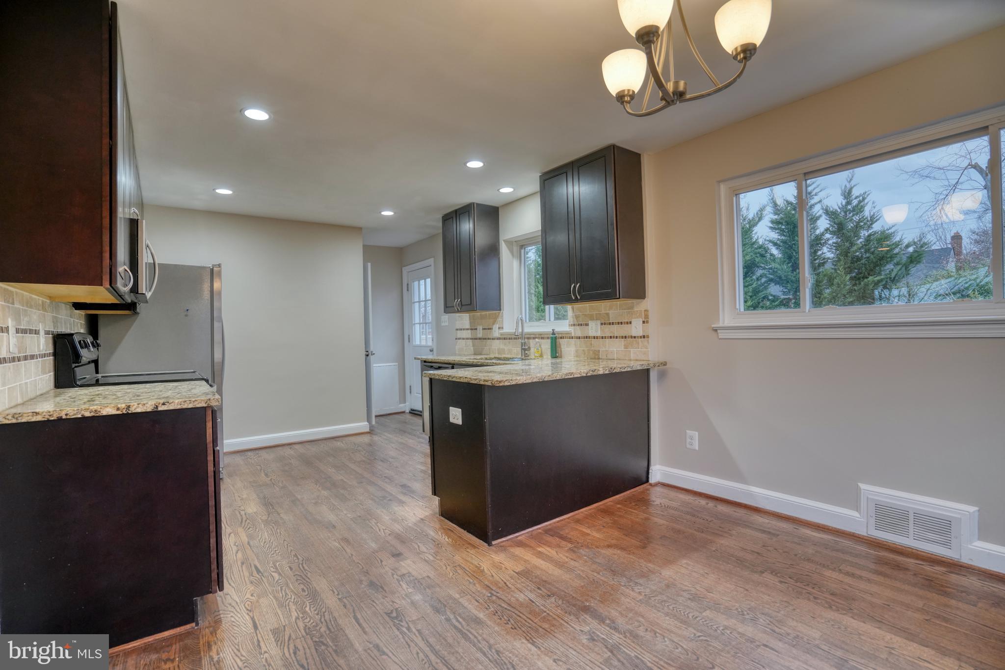 6000 Grayson Street Springfield, VA 22150 - Photo 7 of 37 a kitchen with kitchen island granite countertop a stove and a wooden floors
