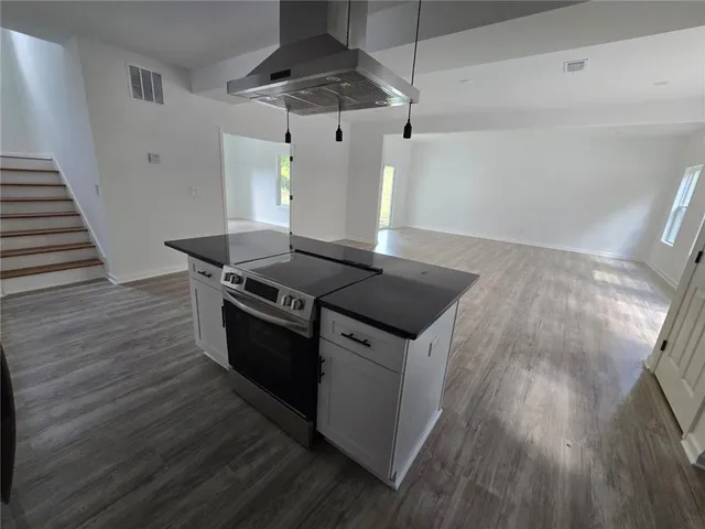 a kitchen with granite countertop a stove and a wooden floor