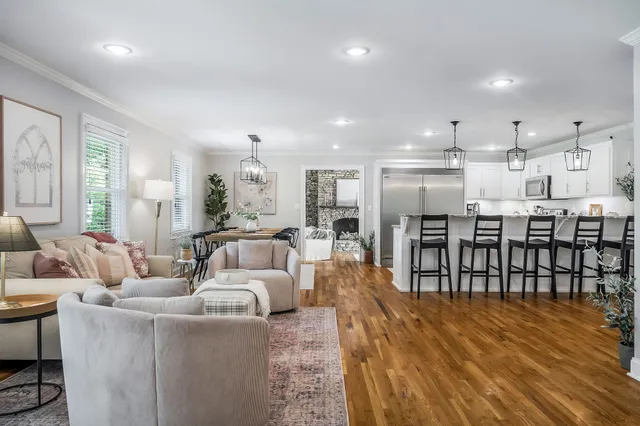 a living room with furniture a wooden floor and kitchen view