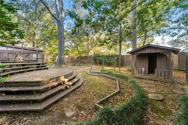 a view of a backyard with plants and large trees