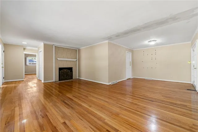 a view of empty room with wooden floor and fireplace