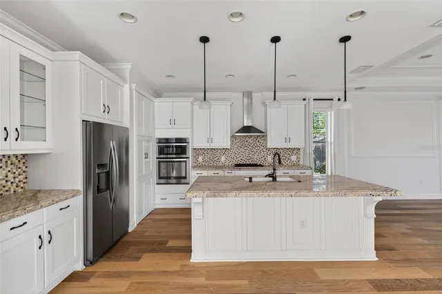 a kitchen with stainless steel appliances kitchen island granite countertop a sink stove and refrigerator