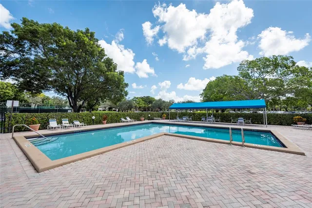 a view of swimming pool with seating space and trees in the background