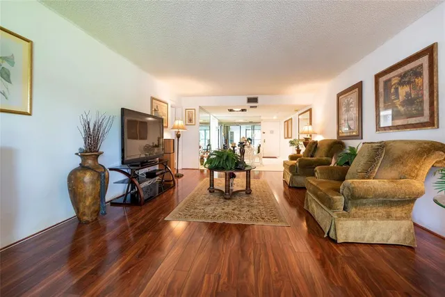 a living room with furniture a flat screen tv and a wooden floor