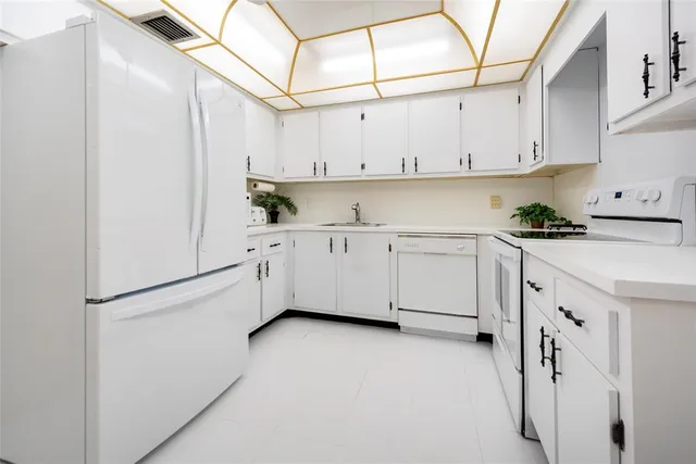 a kitchen with white cabinets and white appliances