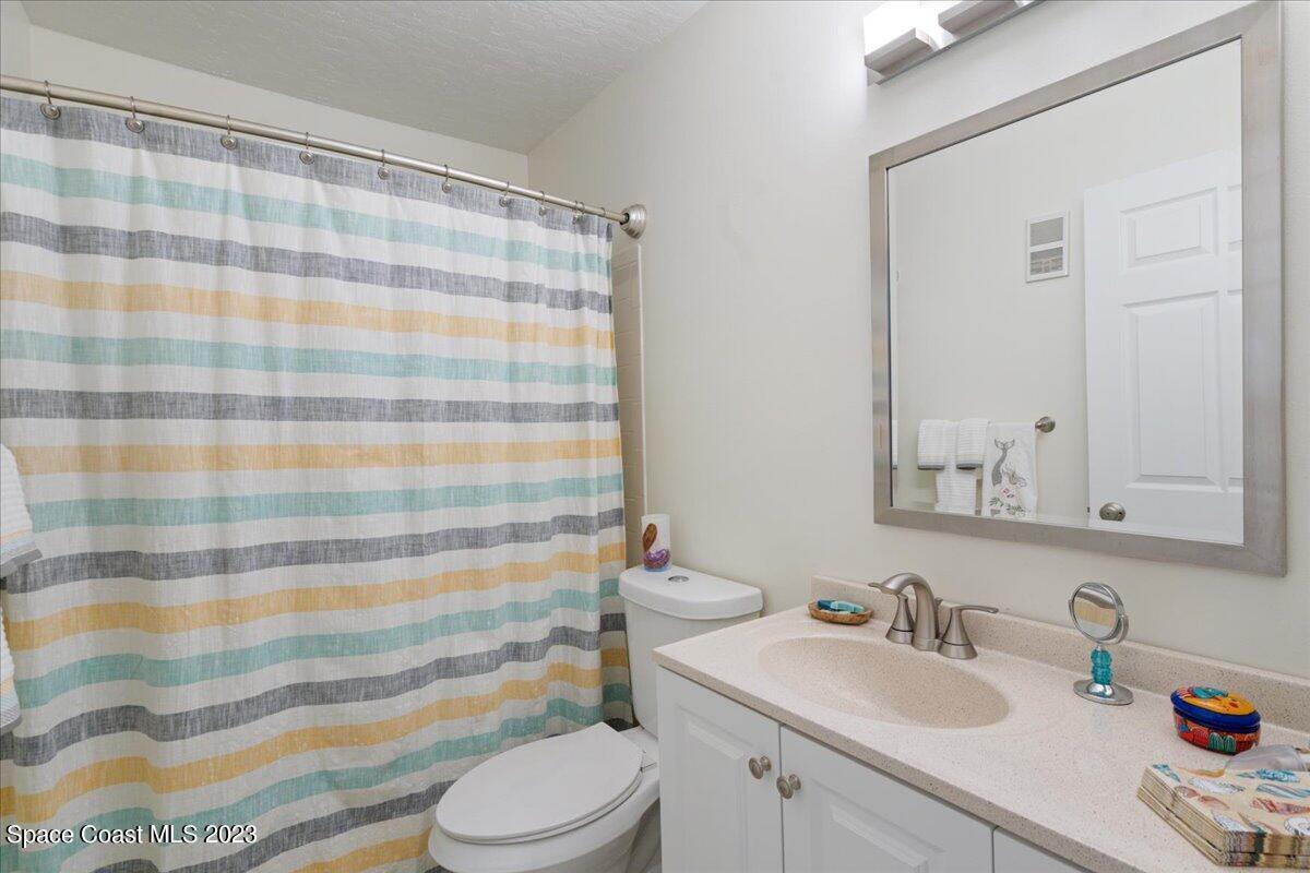 7667 North Wickham Road, Unit 916 Melbourne, FL 32940 - Photo 36 of 53 a bathroom with a sink a toilet a mirror and shower curtain