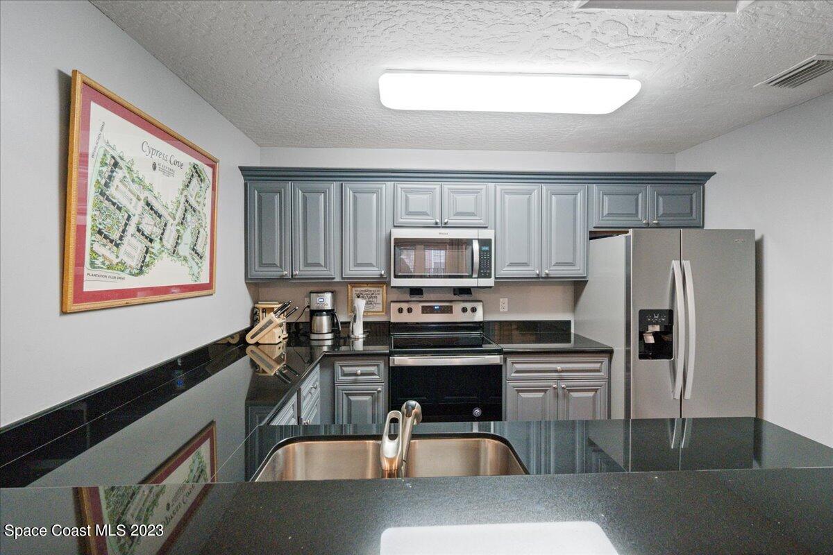 7667 North Wickham Road, Unit 916 Melbourne, FL 32940 - Photo 44 of 53 a kitchen with stainless steel appliances granite countertop a refrigerator a stove top oven a sink and dishwasher