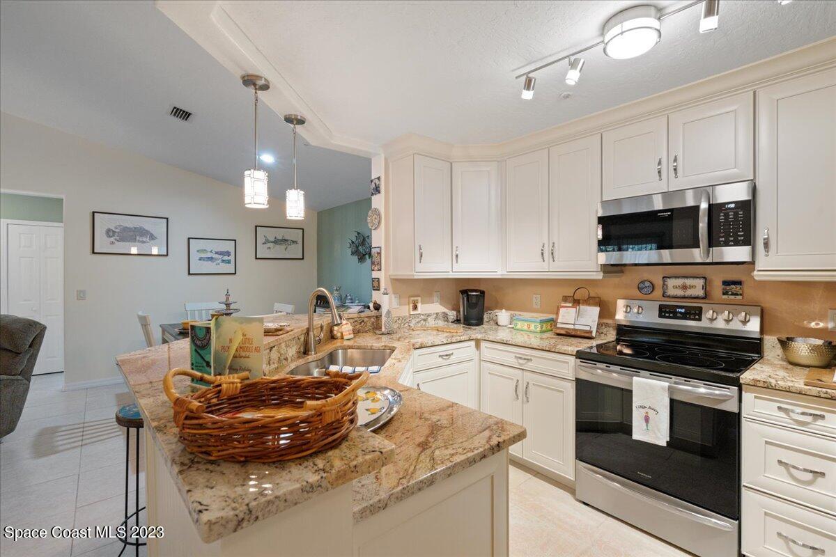 7667 North Wickham Road, Unit 916 Melbourne, FL 32940 - Photo 5 of 53 a living room with stainless steel appliances granite countertop a stove a sink dishwasher and a microwave oven with white cabinets