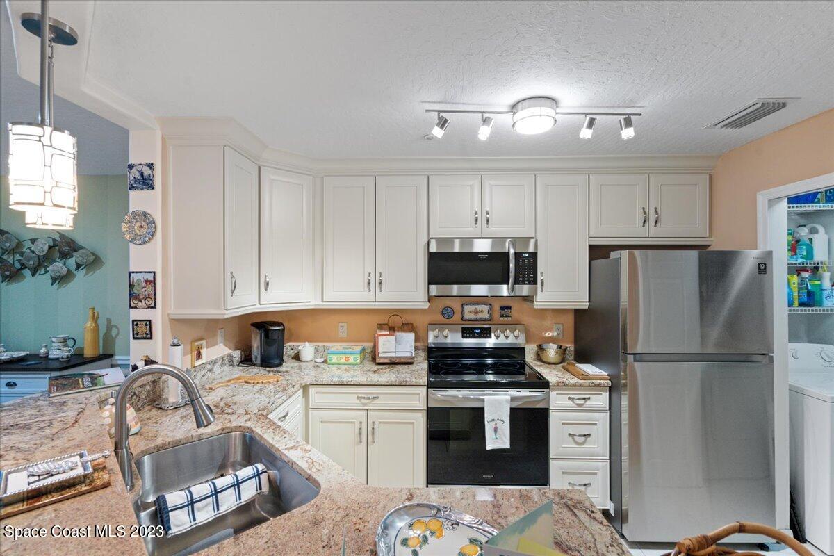 7667 North Wickham Road, Unit 916 Melbourne, FL 32940 - Photo 8 of 53 a kitchen with a refrigerator and a stove top oven