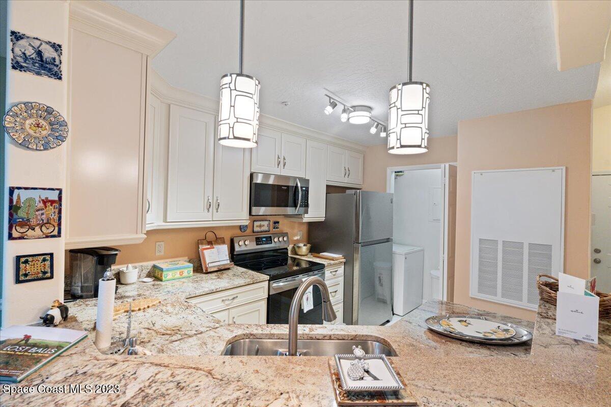 7667 North Wickham Road, Unit 916 Melbourne, FL 32940 - Photo 9 of 53 a kitchen with stainless steel appliances granite countertop a sink dishwasher a refrigerator a stove and a dining table with wooden floor