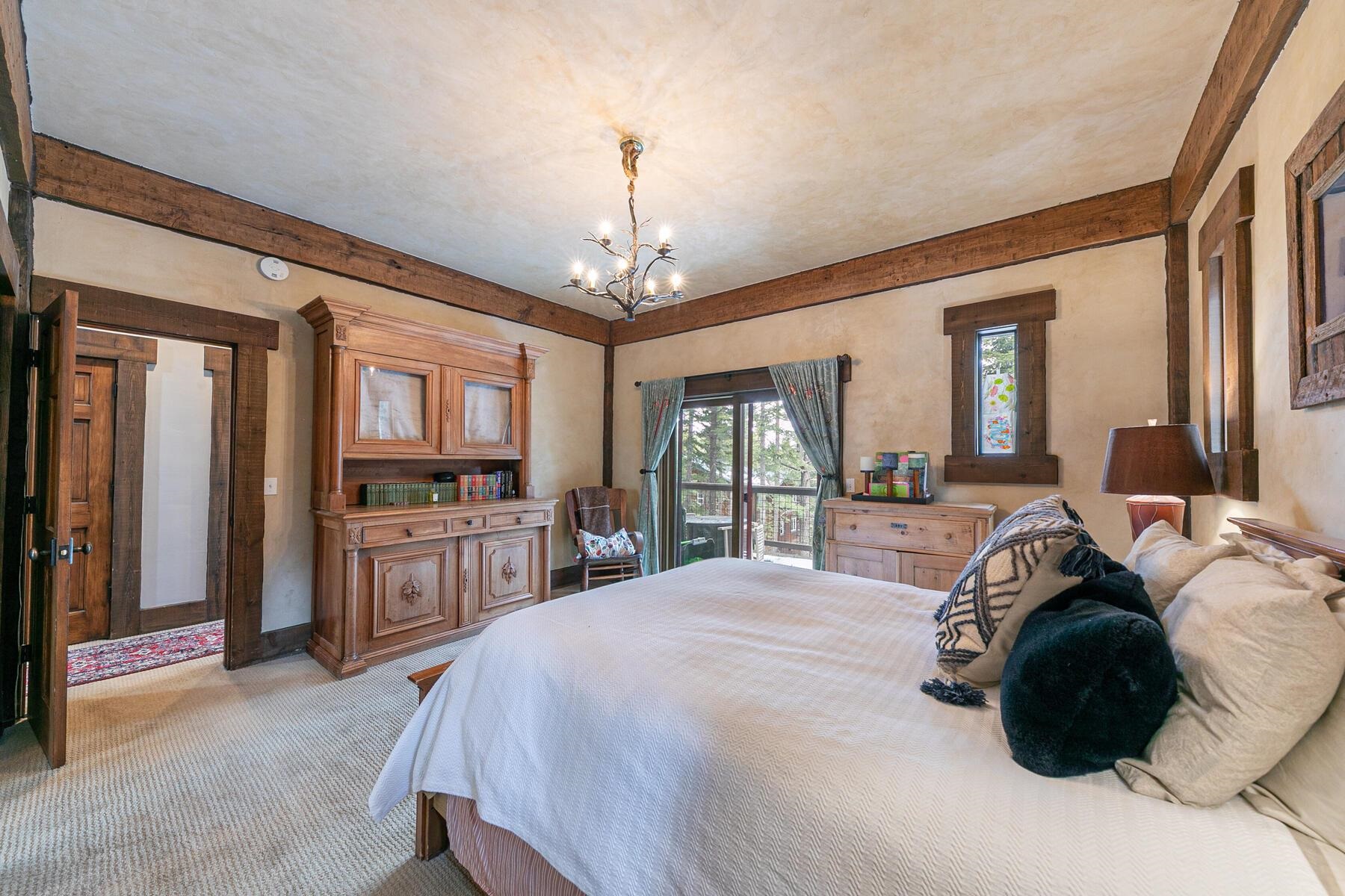 12209 Greenleaf Way Truckee, CA 96161 - Photo 16 of 28 a spacious bedroom with a bed a chandelier and flat screen tv