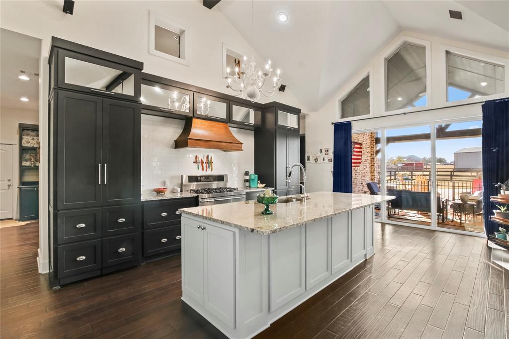 a large white kitchen with a large window and wooden floor