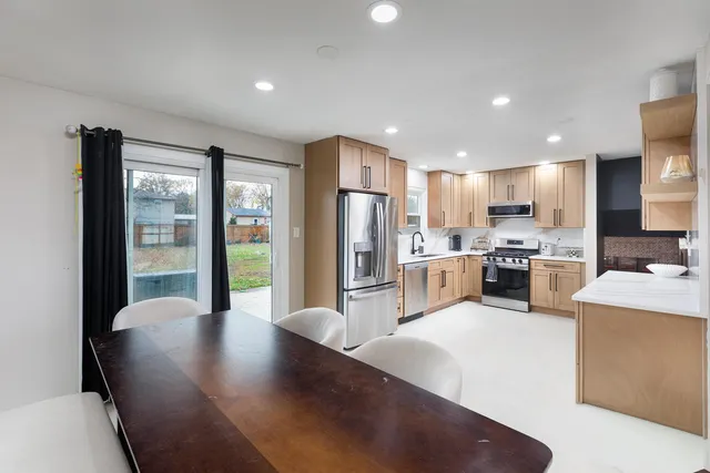 a kitchen with stainless steel appliances granite countertop a refrigerator a sink a stove and white cabinets with wooden floor