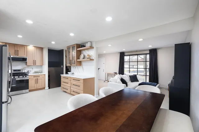 a large white kitchen with kitchen island a refrigerator a stove a sink dishwasher and a dining table with wooden floor