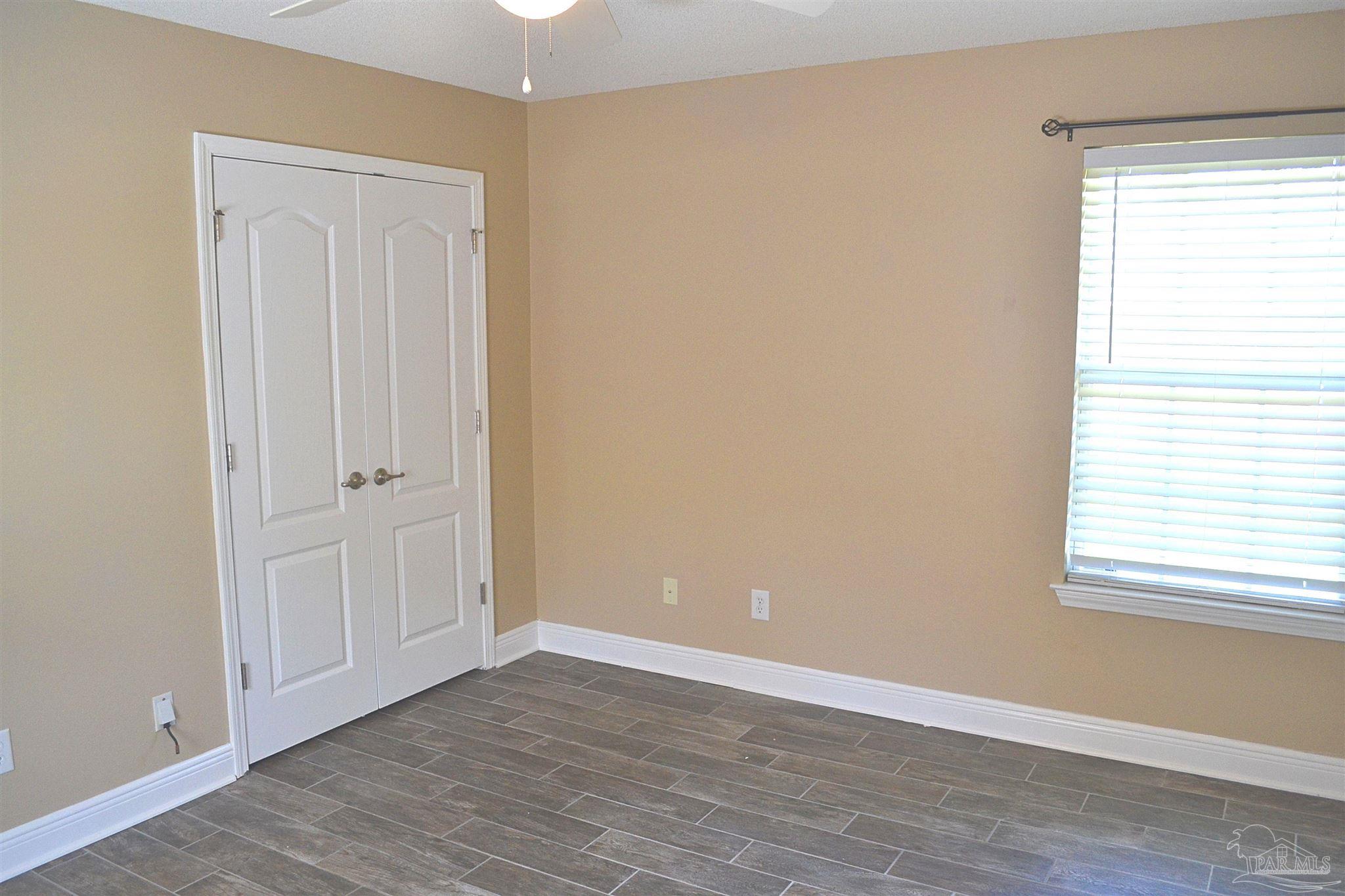 3055 Wallace Lake Road Pace, FL 32571 - Photo 17 of 33 a view of an empty room with wooden floor and a window