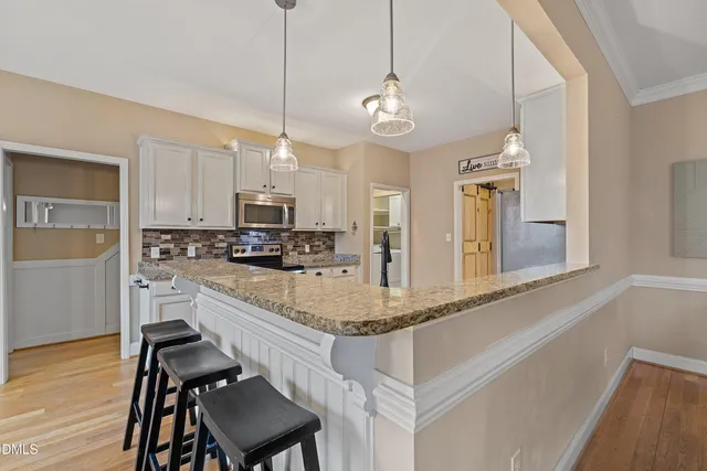 a kitchen with stainless steel appliances granite countertop wooden cabinets a stove a sink and dishwasher with wooden floor