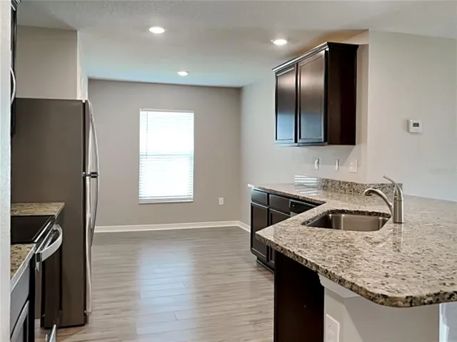 a kitchen with granite countertop a sink and a refrigerator
