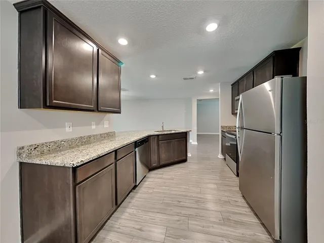 a kitchen with stainless steel appliances granite countertop a refrigerator a sink and a large counter top