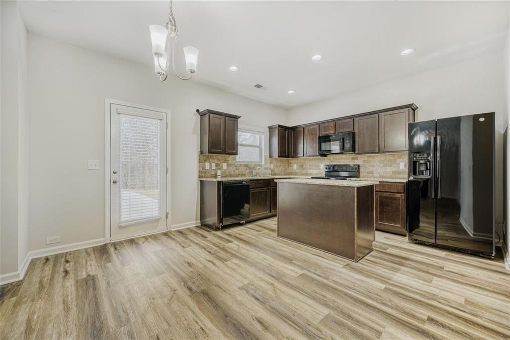 323 Bandelier Circle Hampton, GA 30228 - Photo 12 of 28 a kitchen with stainless steel appliances granite countertop a refrigerator a stove top oven a sink and dishwasher with wooden floor