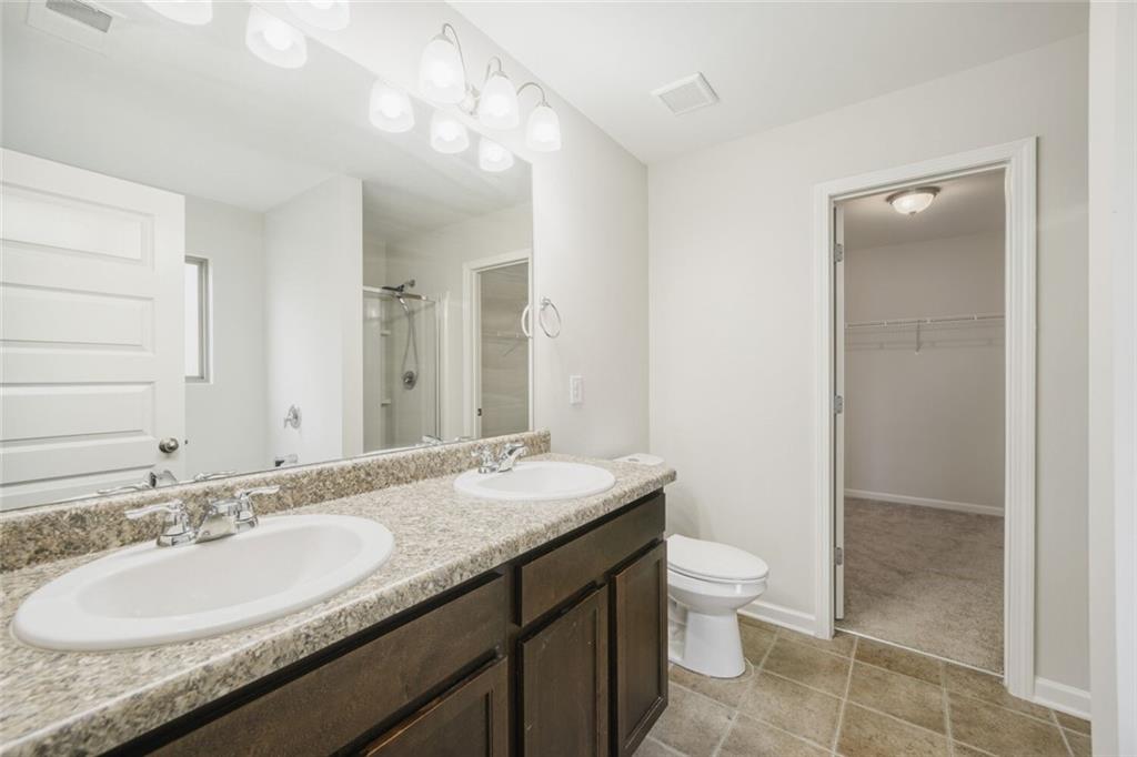 323 Bandelier Circle Hampton, GA 30228 - Photo 23 of 28 a bathroom with a granite countertop sink a toilet a mirror and shower