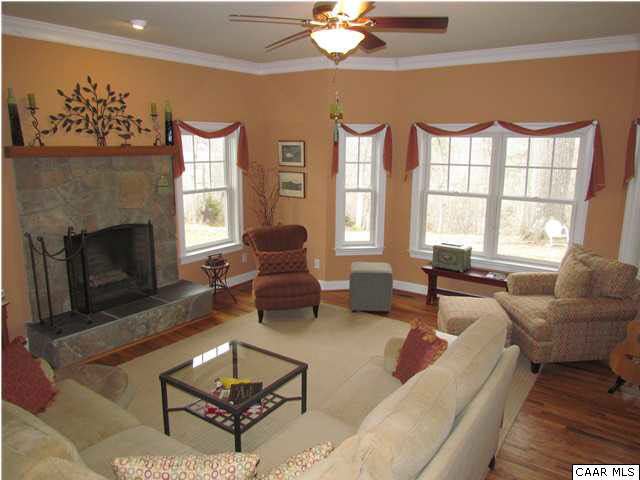 345 Burchs Creek Road Crozet, VA 22932 - Photo 17 of 35 Sunken living room featuring a stone surround, wood burning, masonry fireplace and large bay window to showcase the wonderful mountain views.