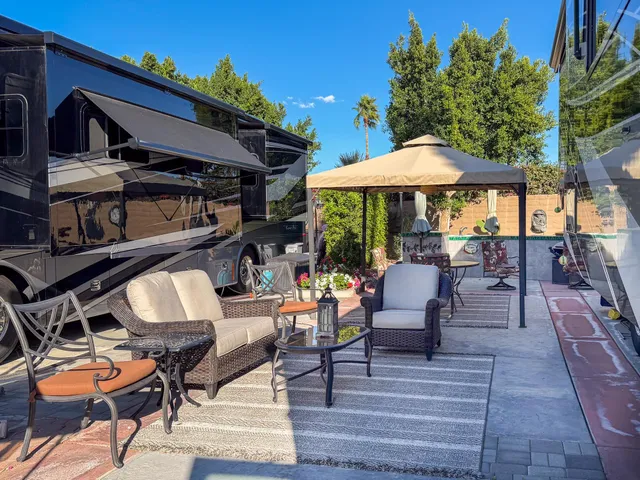 a view of a patio with table and chairs under an umbrella with a barbeque