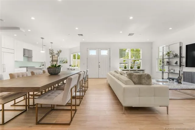 a kitchen with stainless steel appliances granite countertop a stove a sink a refrigerator a center island a dining table and chairs