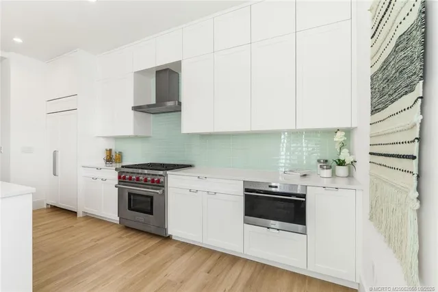 a large white kitchen with a large window a sink and stainless steel appliances