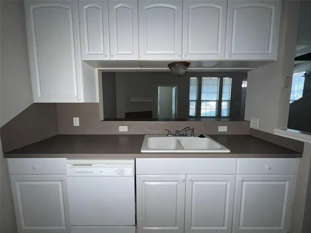 a kitchen with granite countertop white cabinets and a sink