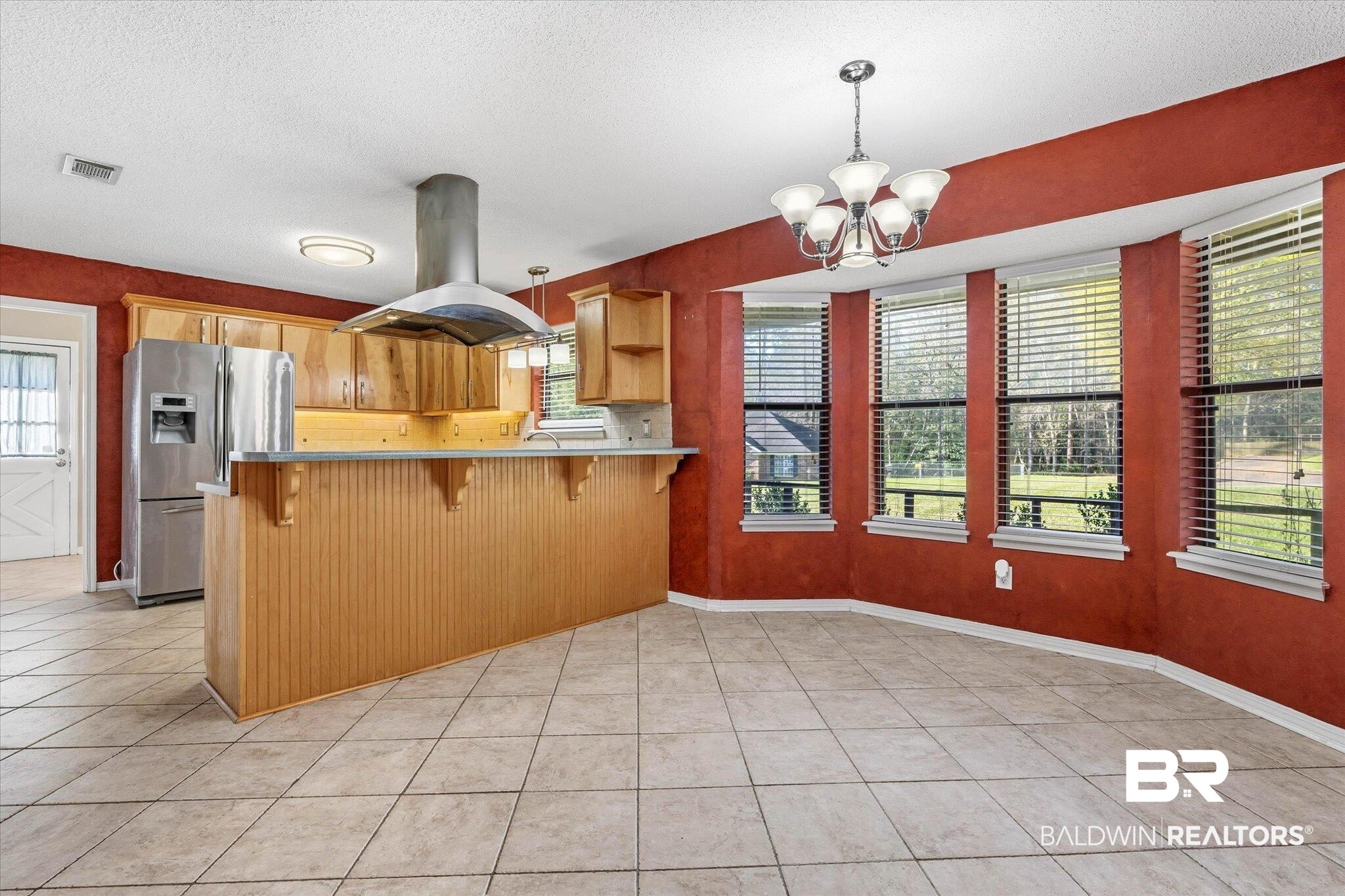 8030 Country Drive Mobile, AL 36619 - Photo 5 of 22 Kitchen featuring a breakfast bar area, stainless steel fridge with ice dispenser, island range hood, hanging lights, and a peninsula