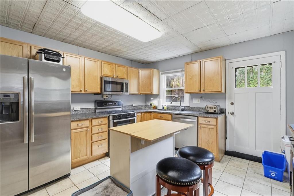 633 Gettysburg Street Pittsburgh, PA 15206 - Photo 10 of 32 a kitchen with stainless steel appliances granite countertop a sink a stove a refrigerator cabinets and a dining table