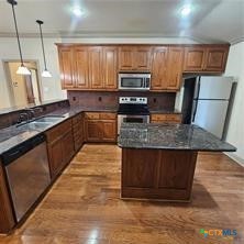 113 Micah Point, Unit B La Vernia, TX 78121 - Photo 3 of 7 a kitchen with stainless steel appliances granite countertop a stove a sink dishwasher a microwave oven and a refrigerator