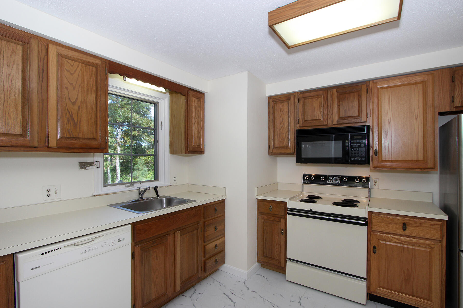 222 Buck Island Road, Unit 53 West Yarmouth, MA 02673 - Photo 8 of 23 a kitchen with stainless steel appliances granite countertop a sink dishwasher stove and microwave with wooden cabinets